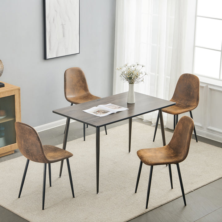 Set of four tan faux suede dining chairs with black metal legs. Curved shell supports the back and a slim frame saves space for kitchens, dining rooms, and apartments.